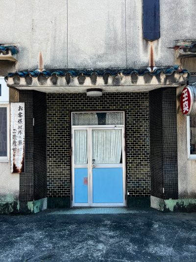 鮮やかな青い瓦屋根とレトロなタイルが美しいエグロ会館のファサード