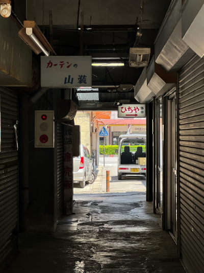 ビル内の薄暗い通路の壁に掛けられたカーテンの山装やひちやの古いレトロ看板