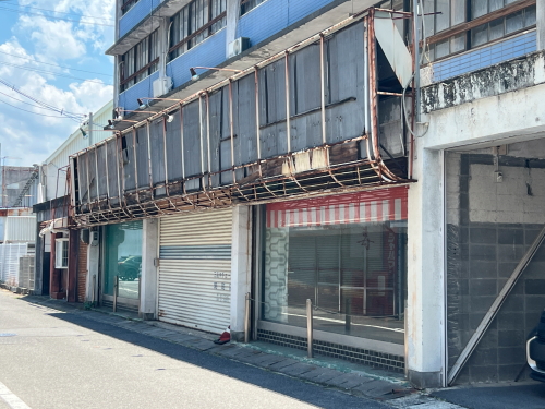 駐車場の奥にある建物の壁面に、大きな四角い看板が取り付けられていた古い台座の跡