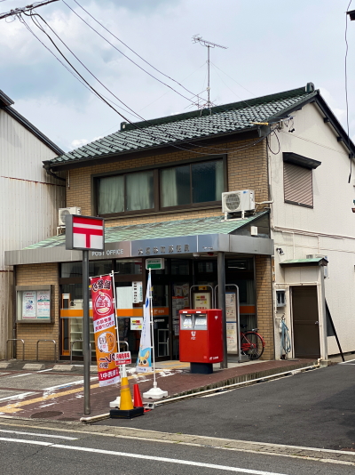 天頂部に古い赤色の郵便マークがあしらわれたポールと、美しい緑青が吹いた大垣林町郵便局の銅板葺き庇
