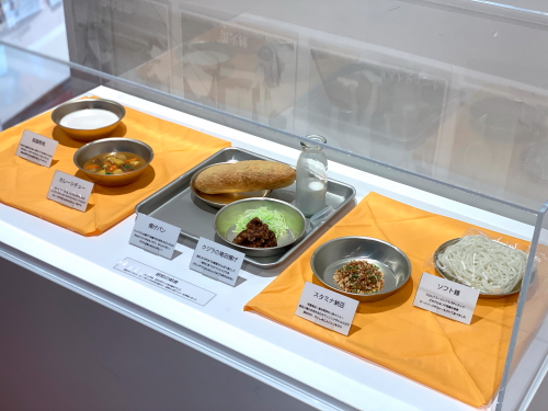 アルマイトの食器やコッペパン、脱脂粉乳が並ぶ昭和の学校給食食品サンプル