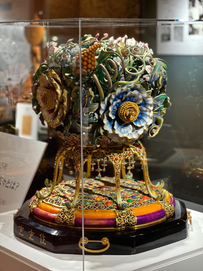 ガラスケースに展示された緻密な彩色彫刻の花かんざし試作品