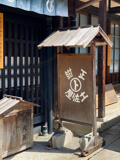 土佐屋の玄関前に掲げられた正紺土佐屋の木製看板と古い消火器箱