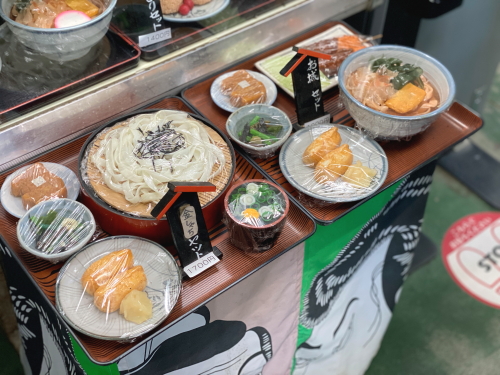 「金シャチセット」や「お城セット」などのボリューム満点な食事セットの立体的な食品サンプル。きしめん、串カツ、いなり寿司などの内容がリアルに再現されています。